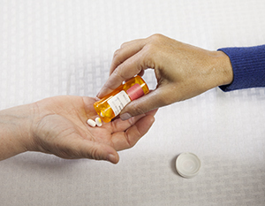 One person putting pills in another person's hand.