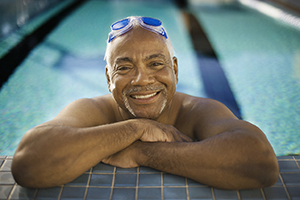Hombre nadando en una piscina, sonriendo.